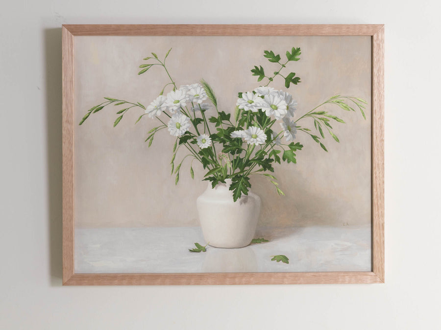 Fine art print framed hanging on a wall.  The print shown is a painting of daisies, grasses and leaves in a white vase with a light beige background.