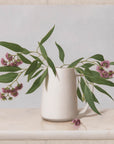 Fine art print of a still life painting of Eucalyptus Blossom in a white vase with a light background.