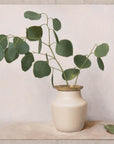 Fine art print of a still life painting of Eucalyptus in a white vase with gold detail and a light background.