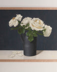 Fine art print framed hanging on a wall. The print shown is of a still life painting of white roses in a black vase with a dark blue background.