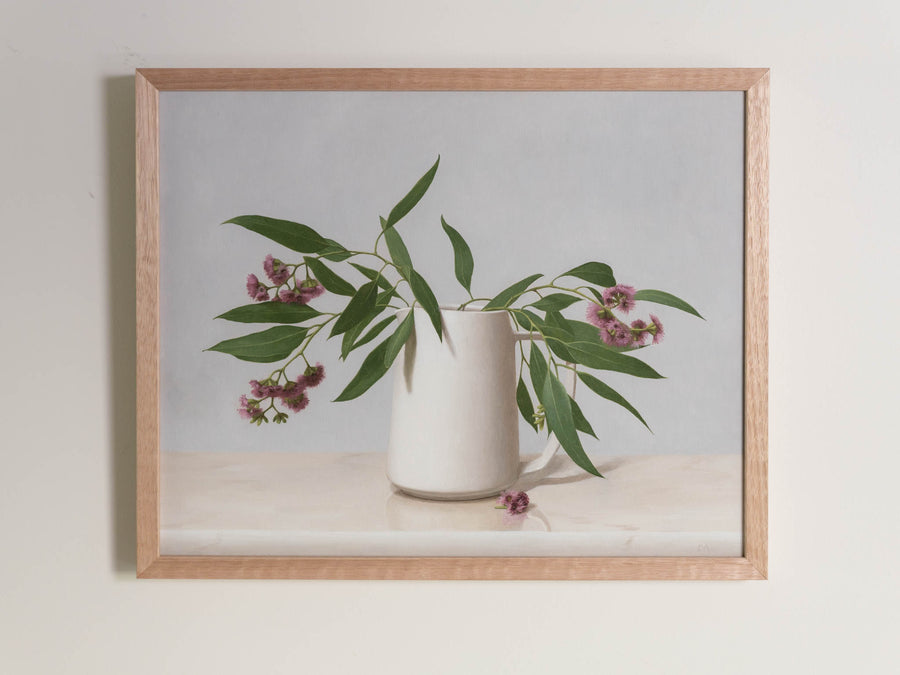 Fine art print framed hanging on a wall. The print shown is of Eucalyptus Blossom in a white vase with a light background.
